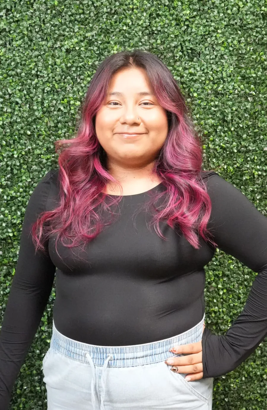 Lucy, esthetician at JM Salon Palm Beach, in front of a wall of green leaves